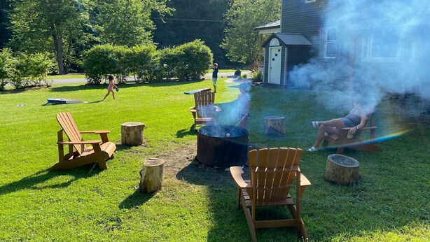 A backyard with a barbecue grill, wooden chairs, and a small shed. - Spacious PA Wilds Getaway! Water views, firepit w/ covered patio (Driftwood)