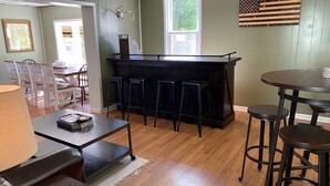 A bar area with stools, a counter, and a flag on the wall. - Spacious PA Wilds Getaway! Water views, firepit w/ covered patio (Driftwood)