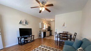 A living room with a TV, a blue sofa, and a patterned rug. - 2 Bed, 2 Bath Topsail Cottage—Walk to the beach! (Myrtle Beach)