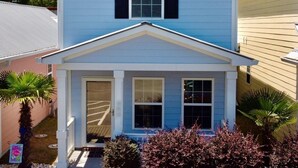 A two-story house with a gabled roof, a front porch with columns, and a small circular window above the entrance. - 2 Bed, 2 Bath Topsail Cottage—Walk to the beach! (Myrtle Beach)