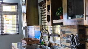 A kitchen with a stainless steel sink, a hanging plant, and a knife block. - Topaz Apartment Villa - Piton View  (Soufrière)