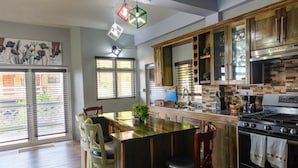A modern kitchen with a central island, wooden cabinets, and a stainless steel stove. - Topaz Apartment Villa - Piton View  (Soufrière)
