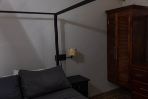A bedroom with a bed, a nightstand, a lamp, and a wardrobe. - Topaz Apartment Villa - Piton View  (Soufrière)