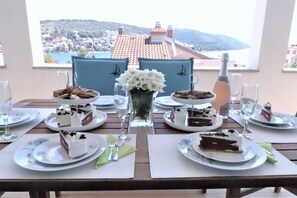 Une table dressée pour un repas, avec vue sur une ville côtière.