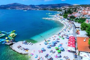 Uma vila costeira com praia, barcos e um mar azul cristalino.