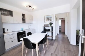 Cozinha moderna com armários brancos, uma mesa de jantar com quatro cadeiras, micro-ondas e máquina de café.