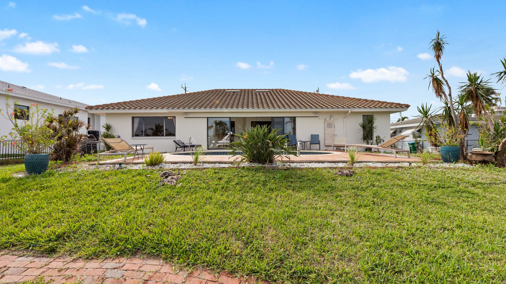 Une maison à deux étages, avec un toit en tuiles, une piscine et une pelouse bien entretenue.