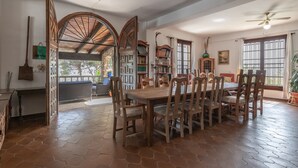 A spacious dining area with a wooden table and chairs, surrounded by bookshelves and a ceiling fan. - ALMARCHADA 38 - Spectacular villa with private pool and free WiFi. (Mijas)