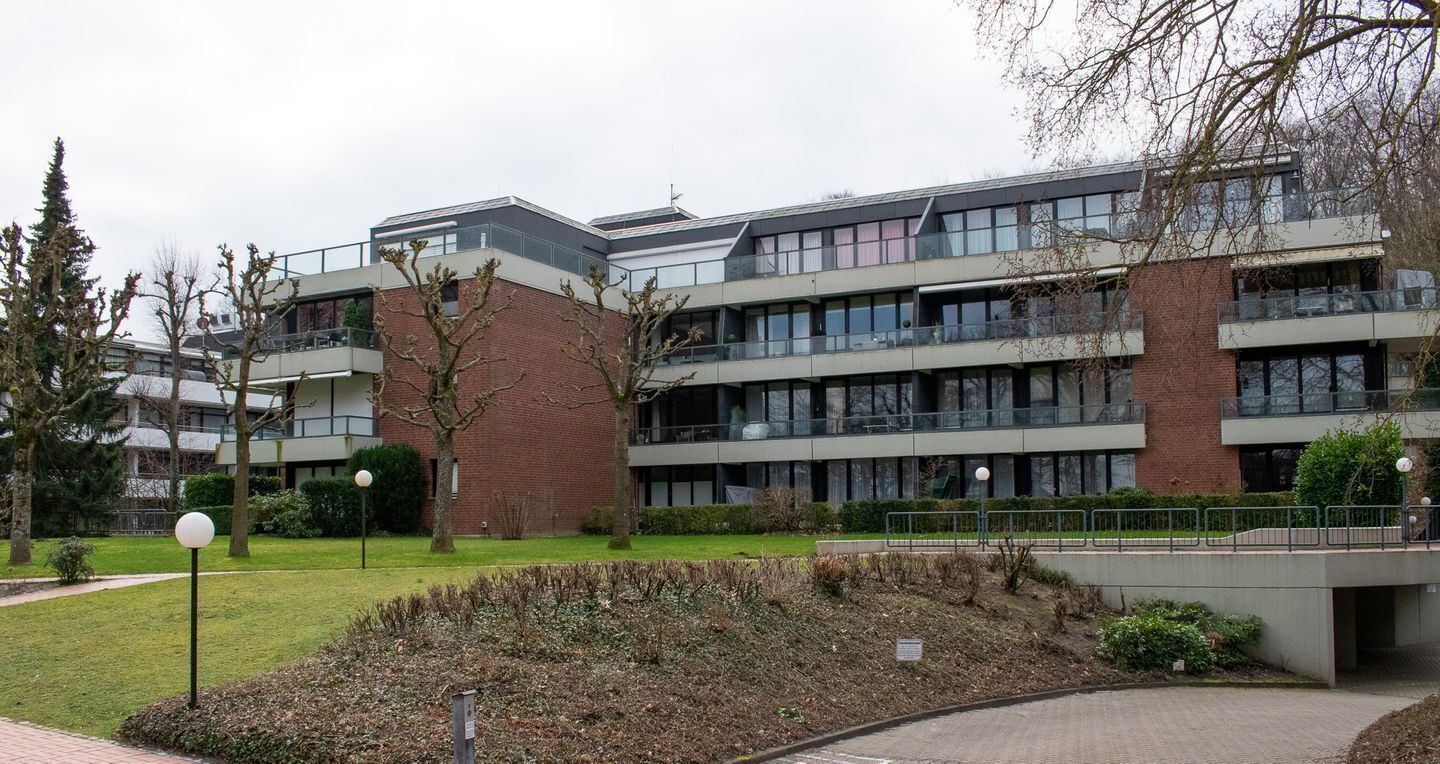 En moderne bygning med flere etager, fladt tag, store vinduer og en murstensfacade.
