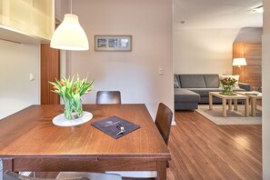 Un espace repas moderne avec une table en bois, des chaises, un vase de fleurs et une suspension.