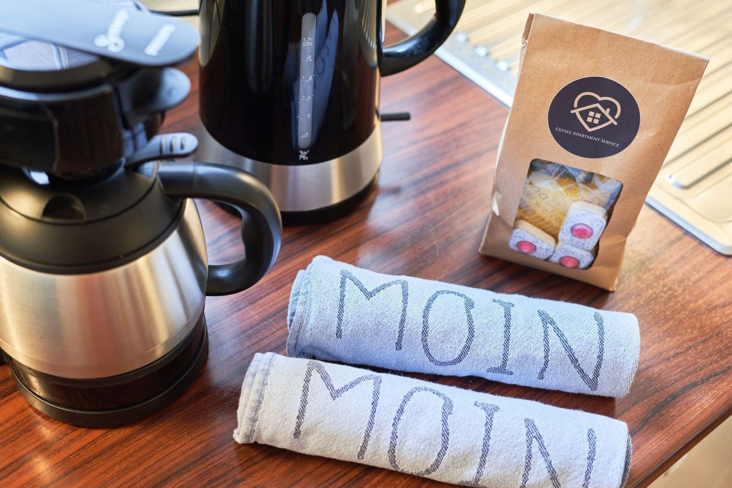 Ett köksutrymme med en kaffebryggare, en vattenkokare och en förpackning kaffekapslar.