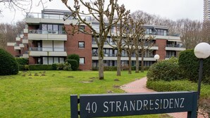 A sign for '40 Strandresidenz' with a modern building in the background.