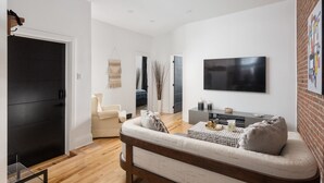 Una sala de estar moderna con sofá, televisión y piso de madera.