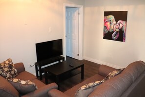 Uma sala de estar com televisão de tela plana, uma mesa de centro e dois sofás.