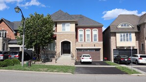 A residential street with houses, parked cars, and a clear sky. - Spacious 3 Bedroom walkout Basement Apartment (Ajax)