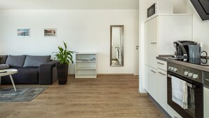 Une cuisine moderne équipée d’un four à micro-ondes, d’un four et d’une machine à café. On y trouve également un canapé et une petite table agrémentée d’une plante.
