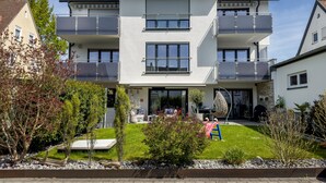 Un immeuble résidentiel à plusieurs étages, doté de balcons, d’une pelouse bien entretenue et d’un petit jardin.
