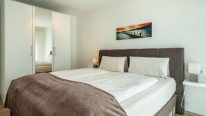 Une chambre à coucher comprenant un lit, une table de chevet, une lampe de chevet, un tableau au mur et une armoire.