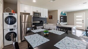 Una cocina moderna con armarios blancos, electrodomésticos de acero inoxidable y un comedor con individuales estampados.