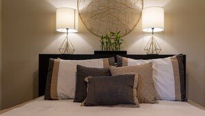 Una cama bien hecha con varias almohadas y cabecero.