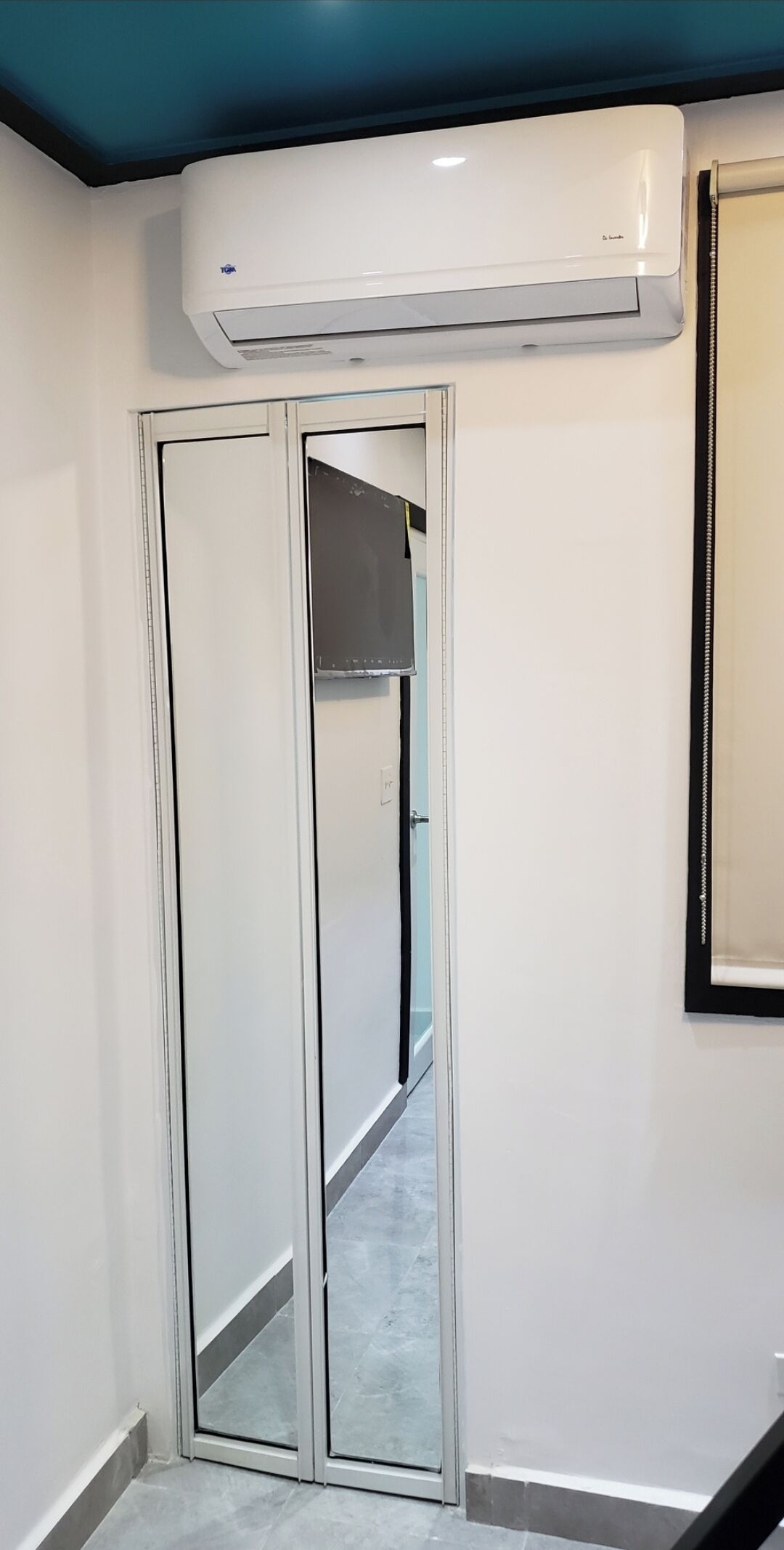 A room with a sliding door, a white air conditioning unit above it, and a framed picture on the wall.