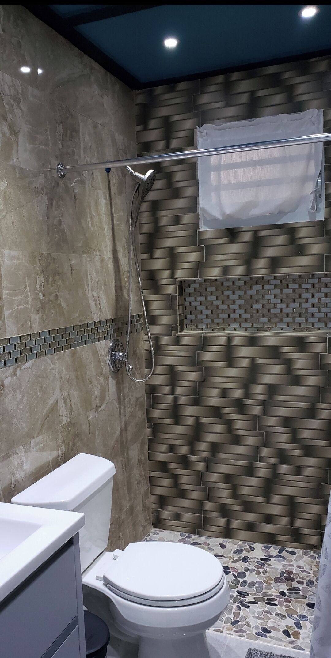 A bathroom with a modern design, featuring a shower with a transparent curtain, a toilet, and a sink.