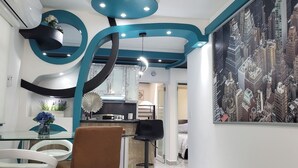 A modern kitchen with a marble countertop, a dining area with a glass table, and a cityscape mural. - (RH)⭕️Los angeles (#1) front of airport (Carolina)