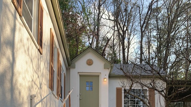 A stone staircase leading to a house with a green door, a small porch, and a light fixture above the door. - Mountainside Cottage (Hot Springs)
