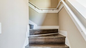 A wooden staircase with white trim and a beige wall. - Joy's Beach Retreat (Pensacola)
