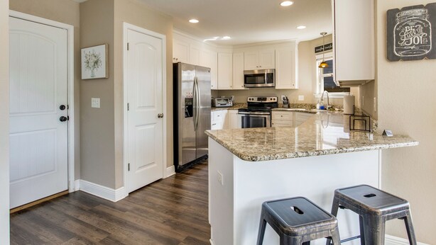 A modern kitchen with white cabinets, stainless steel appliances, and a granite countertop. - Joy's Beach Retreat (Pensacola)