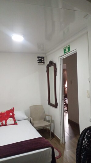 A hotel room with a bed, a chair, a mirror, and a fan. - Wenmel Home (San Andrés)