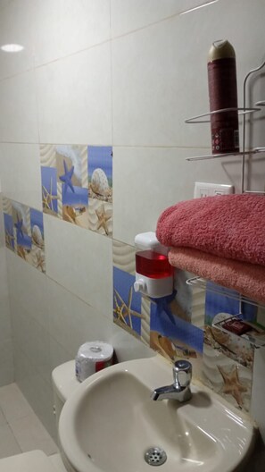 A bathroom with a sink, a toilet, and a towel rack with a rolled towel. - Wenmel Home (San Andrés)