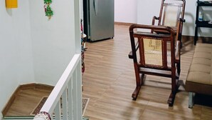 A staircase with a red and white patterned carpet, a wooden chair with a woven backrest, and a beige sofa in a room with wooden flooring. - Wenmel Home (San Andrés)