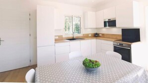 A modern kitchen with white cabinetry, a built-in oven, and a window providing natural light. - Bungalow with terrace close to the Gigaro beach (LA CROIX VALMER)