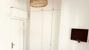 A bedroom with a bed, a chair, a wardrobe, and a television. - Bungalow with terrace close to the Gigaro beach (LA CROIX VALMER)