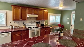 A kitchen with wooden cabinets, a stove, and a tiled floor.