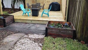 A backyard with a wooden deck, outdoor furniture, and raised garden beds.