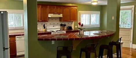 A kitchen with a wooden island, bar stools, and a view of the outside.