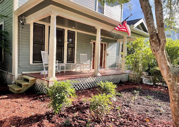 A house with a porch, steps, and a flag.