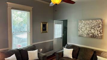 A living room with two sofas, a ceiling fan, and a painting on the wall.