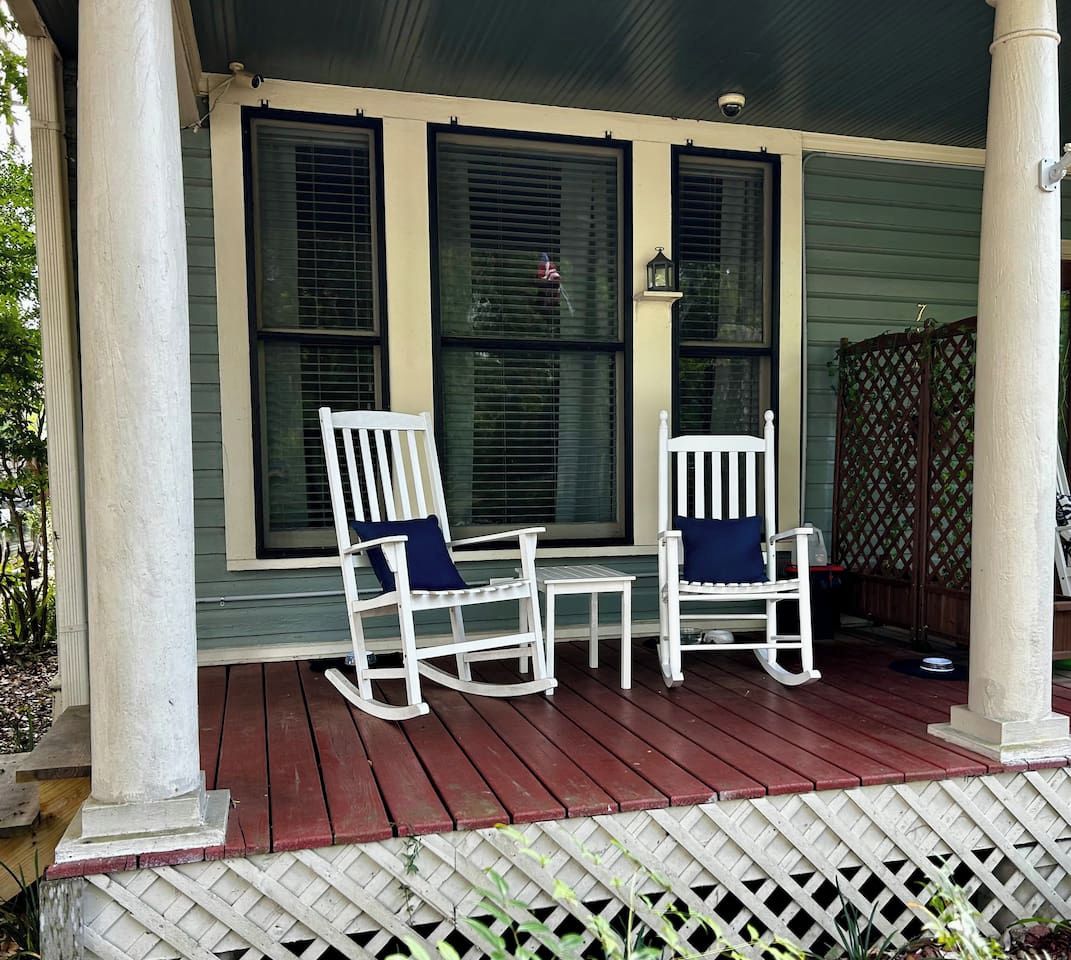 Une véranda avec deux fauteuils à bascule et une petite table.
