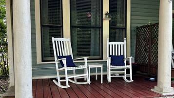 A porch with two rocking chairs and a small table.