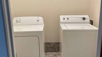 Een wasserette met twee witte wasmachines en een betegelde vloer.