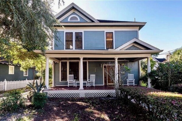 A two-story house with a porch, a picket fence, and a well-maintained garden.