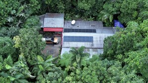 A building with a corrugated metal roof, solar panels, and a red truck parked in front. - Tropical Bliss BNB (Utchee Creek)