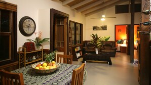A dining area with a table set for two, a bowl of fruit, and a clock on the wall. - Tropical Bliss BNB (Utchee Creek)