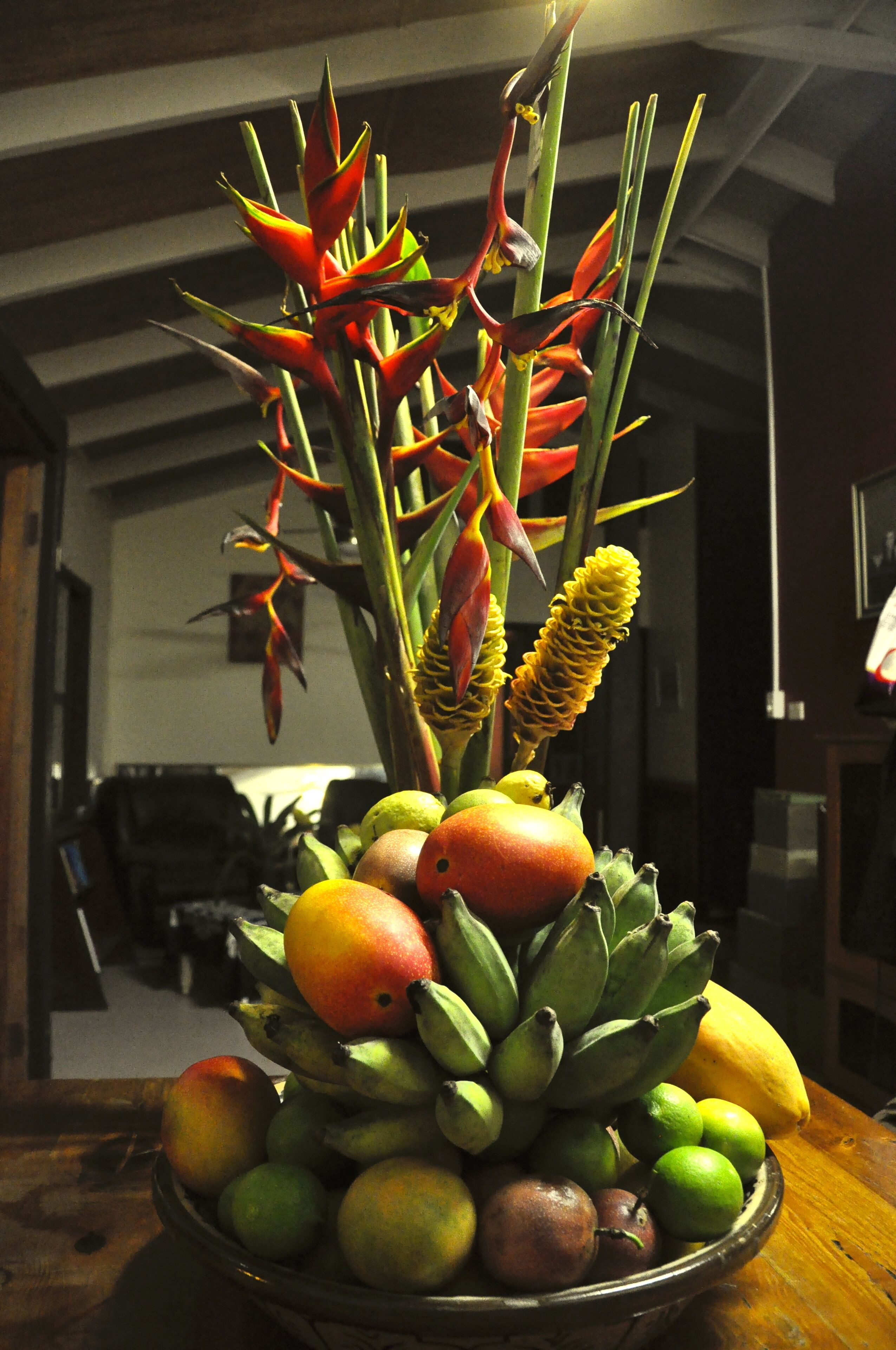 A fruit bowl with bananas, apples, and a decorative plant.