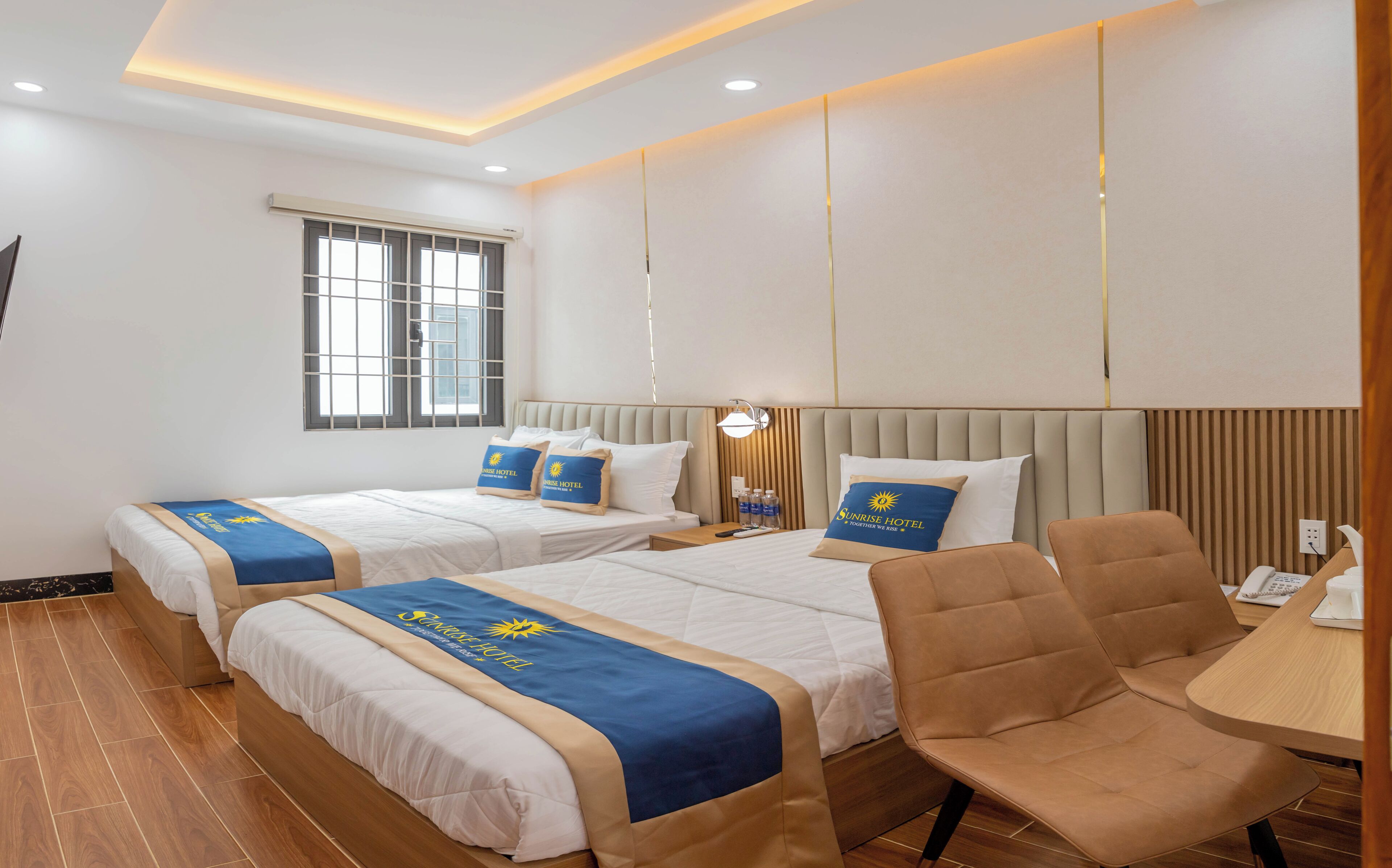 Habitación de hotel con dos camas, un sofá, un escritorio y una ventana.
