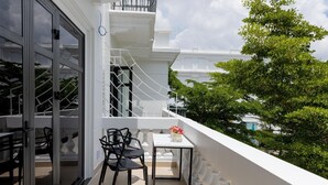 A balcony with a table and chairs, a white railing, and a view of trees and buildings. - SUNRISE Hotel Bac Lieu (Bac Lieu)
