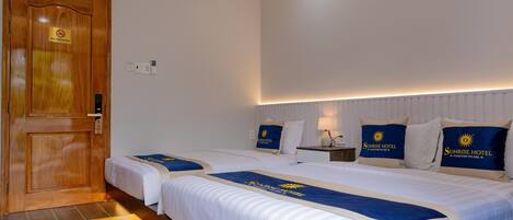 A hotel room with two beds, a wooden door, and a "No Smoking" sign.
